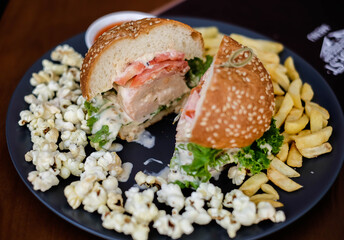 Fast food and unhealthy eating concept, french fries, ketchup and burger on the black plate