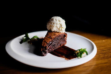 A slice of rich chocolate cake with a scoop of ice cream