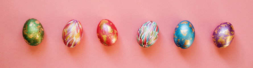 Easter banner made of colorful eggs with gold foil on the pink background.