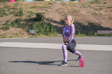 Fototapeta premium Beautiful and sportive blonde girl doing lunges on a street sports ground