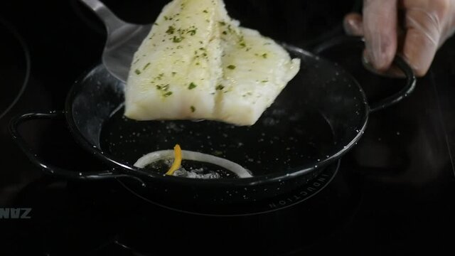 cod fillet preparing it in the pan, with onion bottom, turning it over to seal it, recorded in slow motion