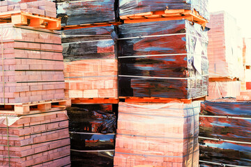 Pallets with red bricks outdoors. Building materials wholesale. pallets and packages of freshly produced red bricks in a construction warehouse on the street. Concept of repair and building materials