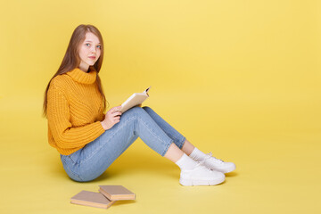 girl reads books and sits on a yellow background