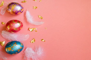 Obraz na płótnie Canvas Colorful Easter, bright eggs, golden foil and white feathers on pink background.