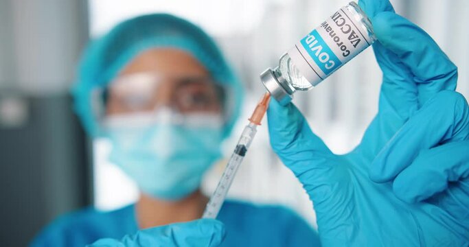 Close up shot of young female healthcare specialist hands holding ampoule with coronavirus vaccine preparing injection for covid vaccination, doctor or nurse in protective uniform work with vaccine - Powered by Adobe