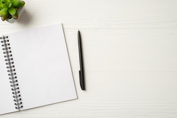 Above flatlay view photo of open clear with empty space copybook on spiral with dark black pen and...