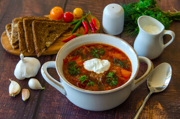 Borscht with sour cream in a beautiful white soup bowl on a wooden table. Traditional Ukrainian and Russian cuisine. 