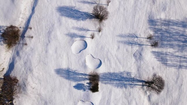 Beautiful shadows from trees in the snow on a golf course one sunny but cold winter day in Gothenburg, Sweden. 4K aerial footage.