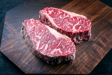 Modern style raw dry aged wagyu roast beef steak offered as top view on a wooden design board