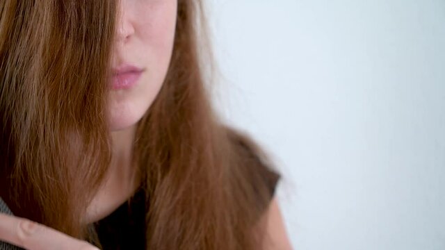 The girl smiles and combs her long red hair in close-up