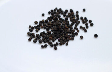 Few black peppers on white background