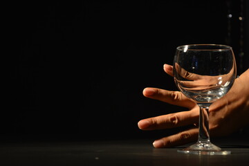 Cropped Hand Seen Through Wineglass Against Black Background