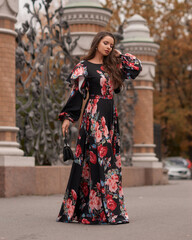 Young beautiful caucasian woman with long straight brunette hair in colorful dress walking at city street