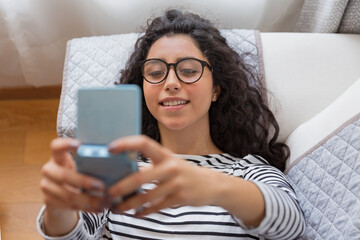 Shot from above of a beautiful young woman enjoying lying on the sofa at home she is happy with her...