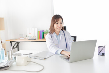 Asian female doctor typing report with laptop, she feeling happy and relax in hospital