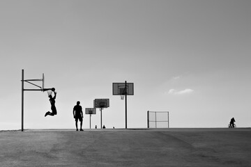 silhouette of basketball players on a street court  © Andy
