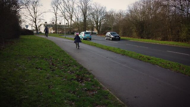Young girl riding her bike on bike lane next to the road. She is wearing safety helmet