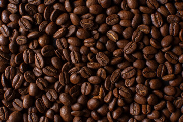 Fresh roasted coffee beans closeup on black stone background. Food pattern. Top view, flat lay with copy space
