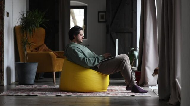 man working on outsource with laptop and playing with dog in same time at home