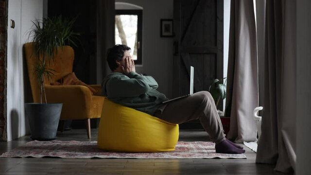 man working on outsource with laptop and playing with dog in same time at home