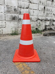 Orange traffic cone (With white and orange stripes) placed on the gray asphalt road in the parking...