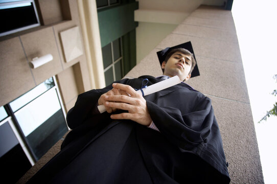 Low Angle Portrait Of Man Wearing Mortarboard Holding Certificate