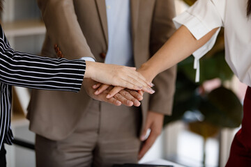 Obraz premium close up view of young businesspeople putting their hands together showing a good teamwork. Stack of hands. Unity, teamwork, cooperation successful concept