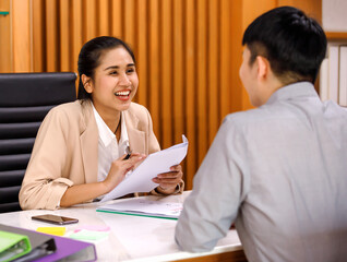 young attractive Asian businesswoman dressed smart casual smiling friendly and cheerful to the applicant during the interview in a company office. Confident and successful people concept