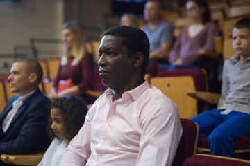 portrait of african viewer sitting at premiere in theatrical hall