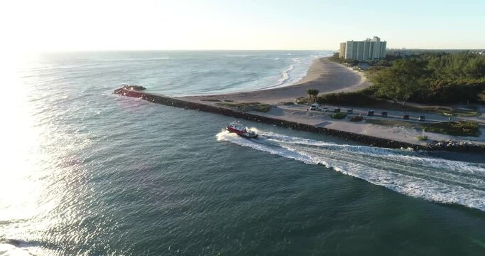 Aerial tracking shot of a towboat traversing the waves of Jupiter Inlet to get out to sea.