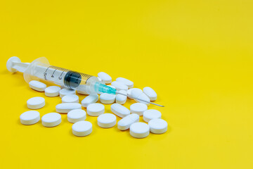 Syringe and pills on yellow background. Medical concept