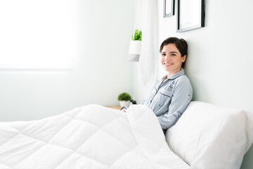 Attractive young woman lying in her white bedroom