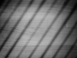 Black and white texture of wooden table background with blurred striped light.