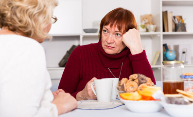 Obraz na płótnie Canvas Pensioners females quarreling at kitchen near food at the table