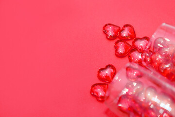 two glasses with hearts on a red background. the view from the top. red hearts spilled out of the glasses. isolated on a pink background. copy space