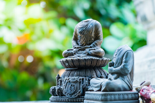 Broken Buddha Statues Against Plants