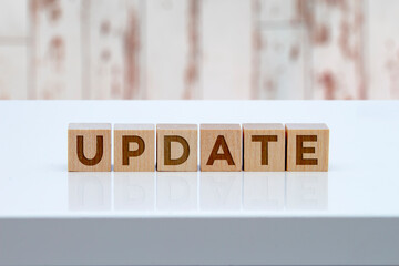 'Update' message sign on wooden blocks sitting on a white table with wooden wall on the background.