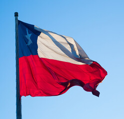 Flag of Chile flying in the wind on flagpole in clear blue sky