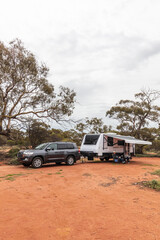 Potrtrait view of retired Australian senior citizens known as "Grey Nomads" relax and enjoy a cup of coffee outside of their modern caravan while camped in the outback.