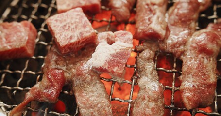 Close up grilling sliced meat beef on iron cast grate charcoal grill barbecue in a flame of fire and smoke