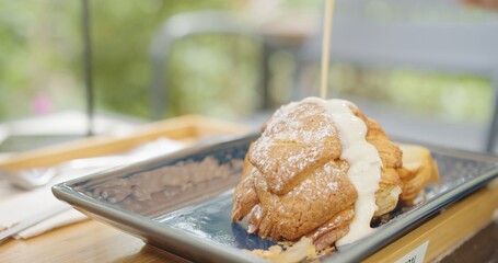 Pouring white cream sauce into fresh homemade Croissant bread , morning breakfast meal