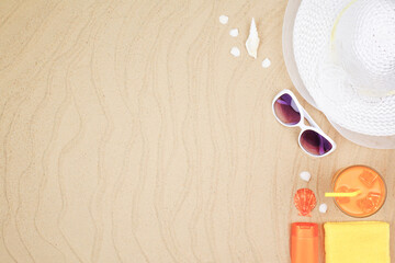 top view travel beach background concept with sunglasses ,orange juice , sunscreen and beach hat on sand.