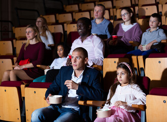 mother, father and their children sitting at film in auditorium