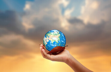 Hand holding the earth on dry leaf save the earth concept. sun set background.