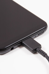 Plug of charger connected to mobile phone. Smartphone charging