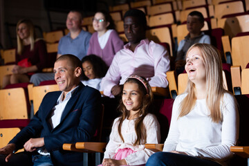 parents with children laughting at movie in cinema