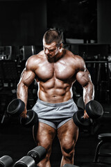 Fototapeta na wymiar Athlete muscular bodybuilder in the gym training with dumbbells
