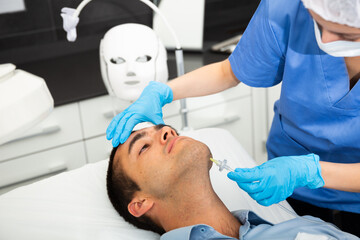 Obraz na płótnie Canvas Male client getting carbon dioxide injections for face skin rejuvenation in clinic of aesthetic cosmetology.