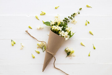 white flowers jasmine local of asia arrangement in brown paper cone arrangement flat lay style on background white wooden