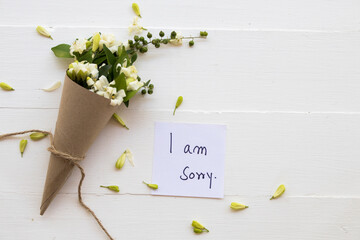 i am sorry message card handwriting with white flowers jasmine in paper cone arrangement...